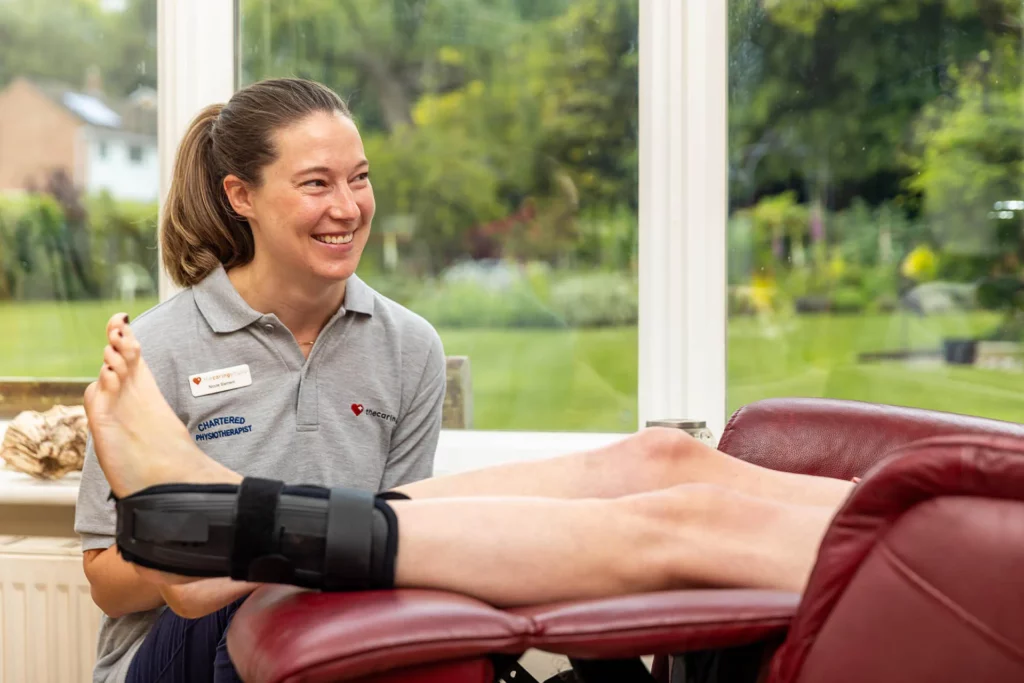 Caring Physio chartered physiotherapist supporting a patient's lower leg in an ankle brace at home
