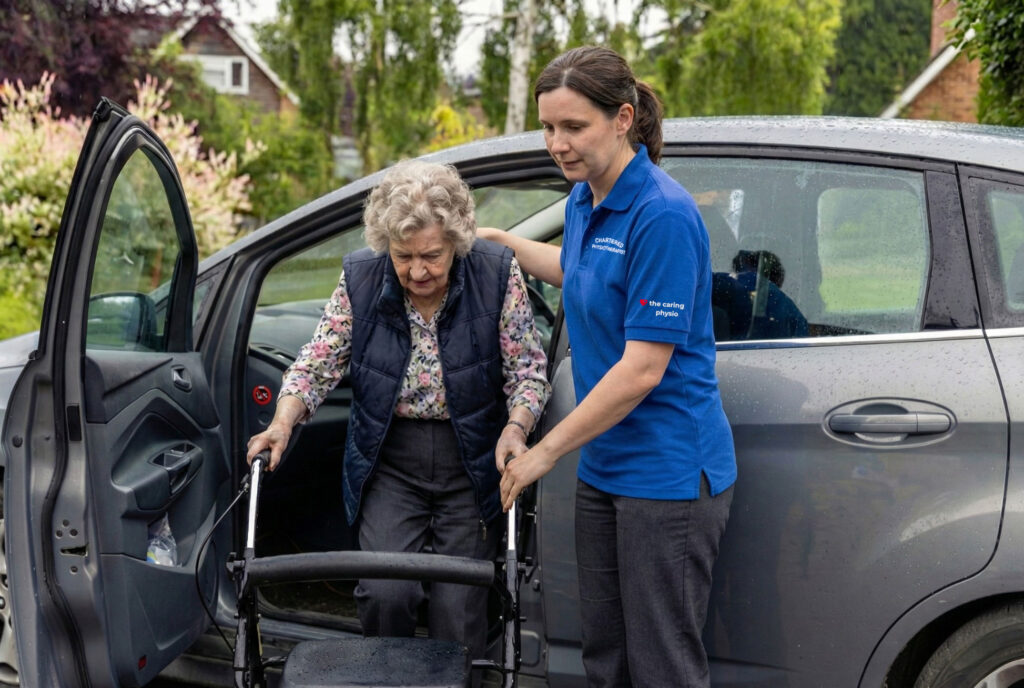 Chartered physiotherapist helping an older patient with a mobility transfer during a home visit in Berkshire.