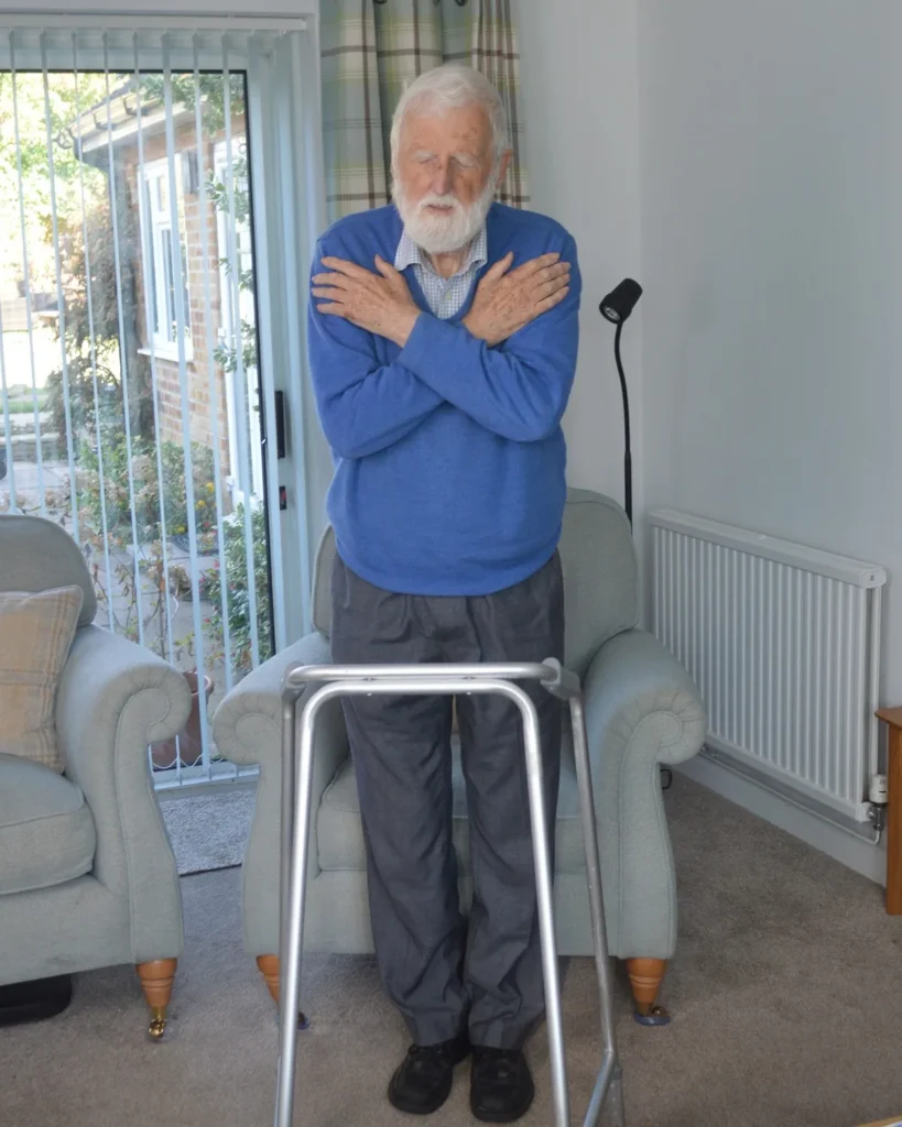 Older man standing with feet together and arms crossed for Romberg's balance test